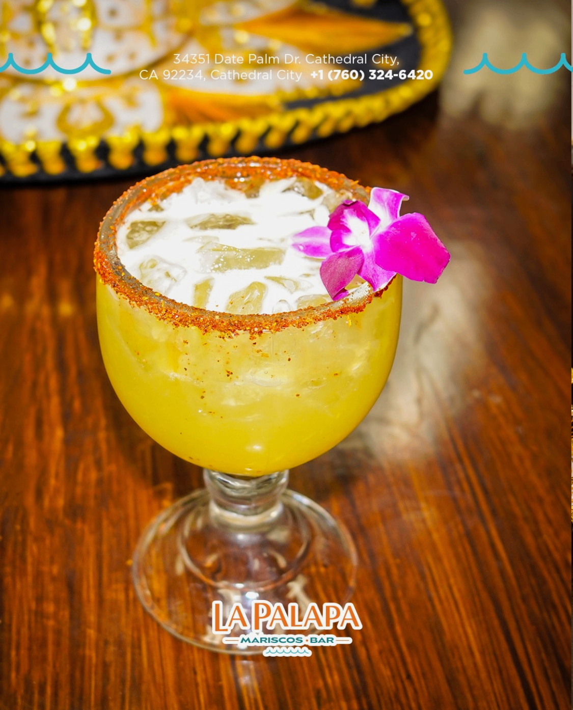 House cocktail with a chile-seasoned rim and flower garnish.