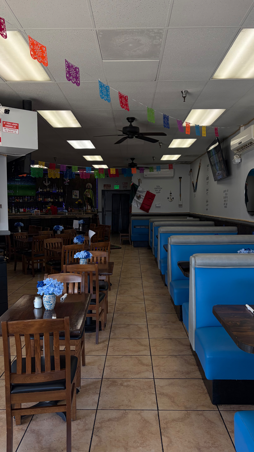 The bright dining room at La Palapa with blue booths and papel picado banners.